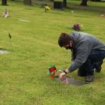 Pablo Closson decorates a veterans grave at Maple Leaf Cemetery.