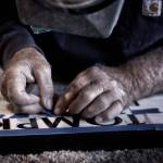 Artist Woody Morris works on the lettering of a stone memorial.