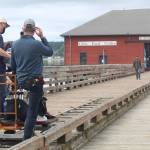 Chris Stack and Samantha Soule film a scene of their movie, Midday Black, Midnight Blue, on the Coupeville wharf June 14. (Photo by Karina Andrew/Whidbey News-Times)