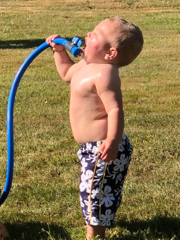 Ian Lambert, 13 months old, plays with a hose to stay cool.