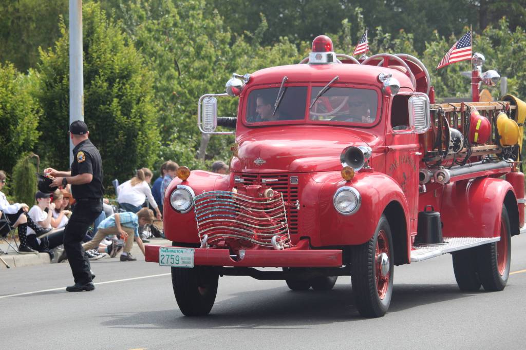 A local firefighter throws candy to kids watching the parade. (Photo by Karina Andrew/Whidbey News-Times)