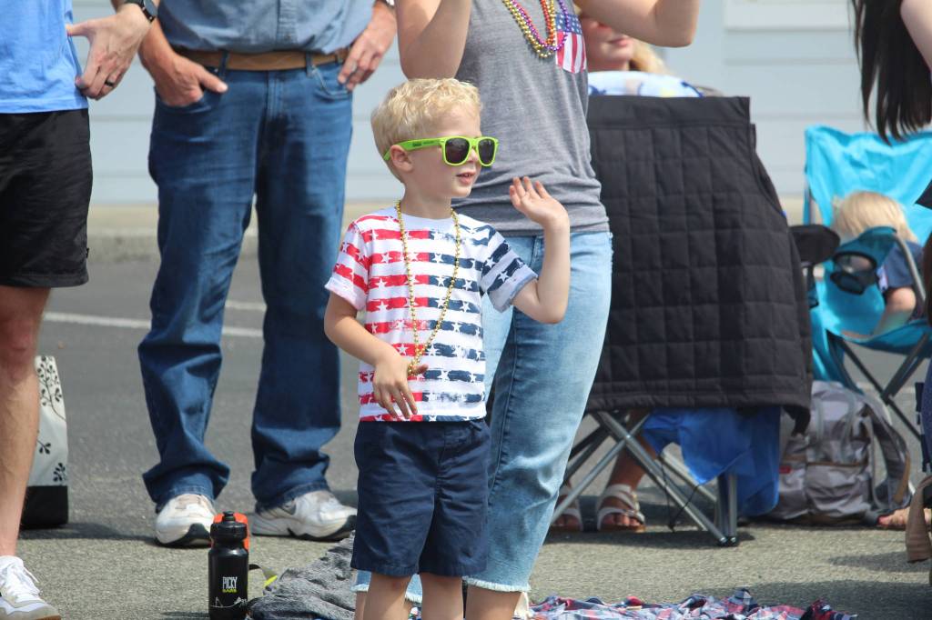 Adam Gordon, 3, waves at people in the parade as they pass by. (Photo by Karina Andrew/Whidbey News-Times)