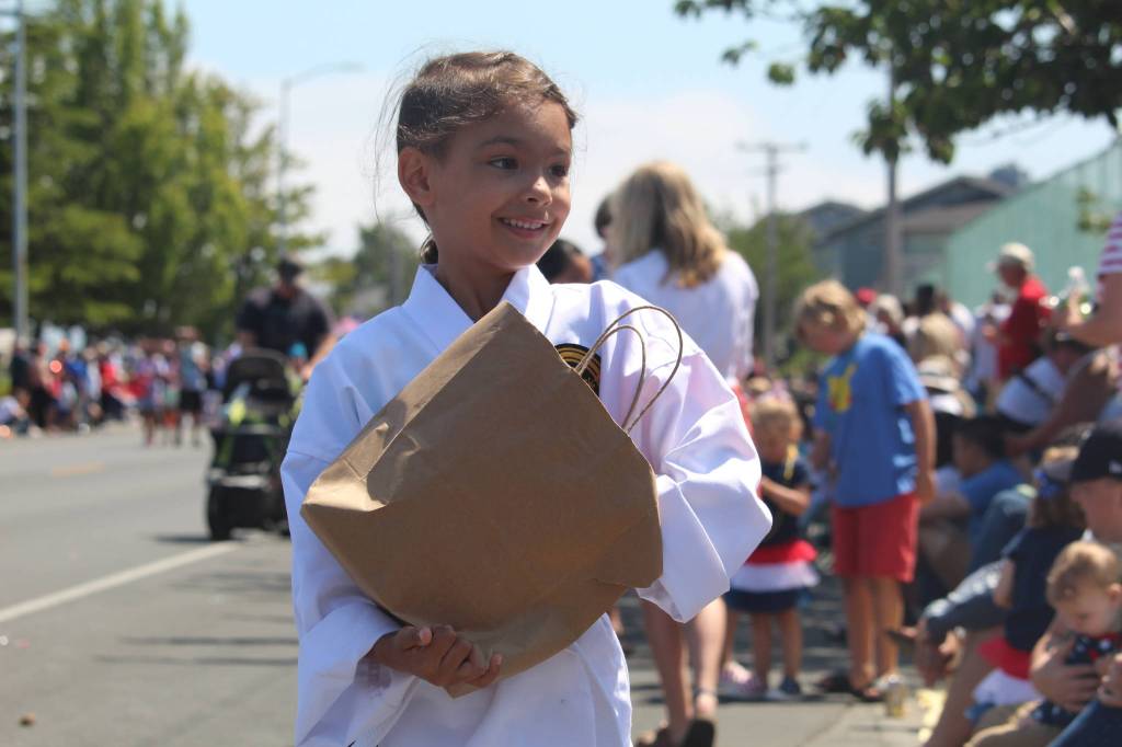 A young girl hands out candy to parade watchers. (Photo by Karina Andrew/Whidbey News-Times)