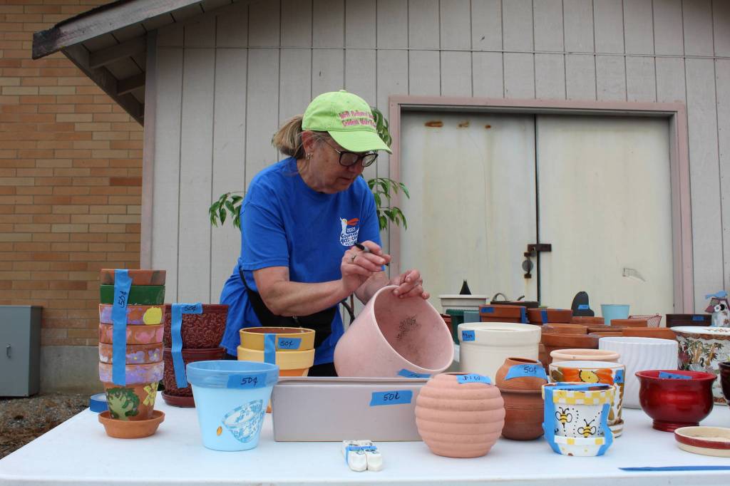 Lions Club member Marilyn Pulk prices pots to be sold at the garage sale this weekend. (Photo by Karina Andrew/Whidbey News-Times)