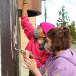 Photo by Karina Andrew/Whidbey News-Times
Oak Harbor High School junior Kaydence Murdock, front, and artist Nikita Ares paint the wall where the next Allgire Project mural will go.