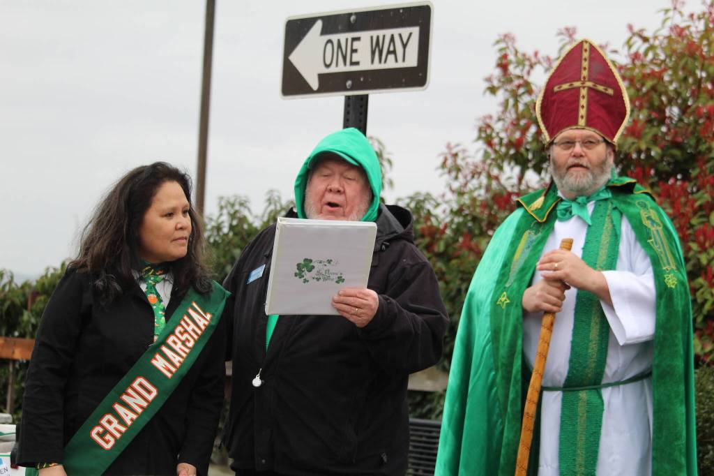 Parade Marshal Maria McGee, Pastor David Lura and Oak Harbors own St. Patrick give a blessing at the Blarney stone.
