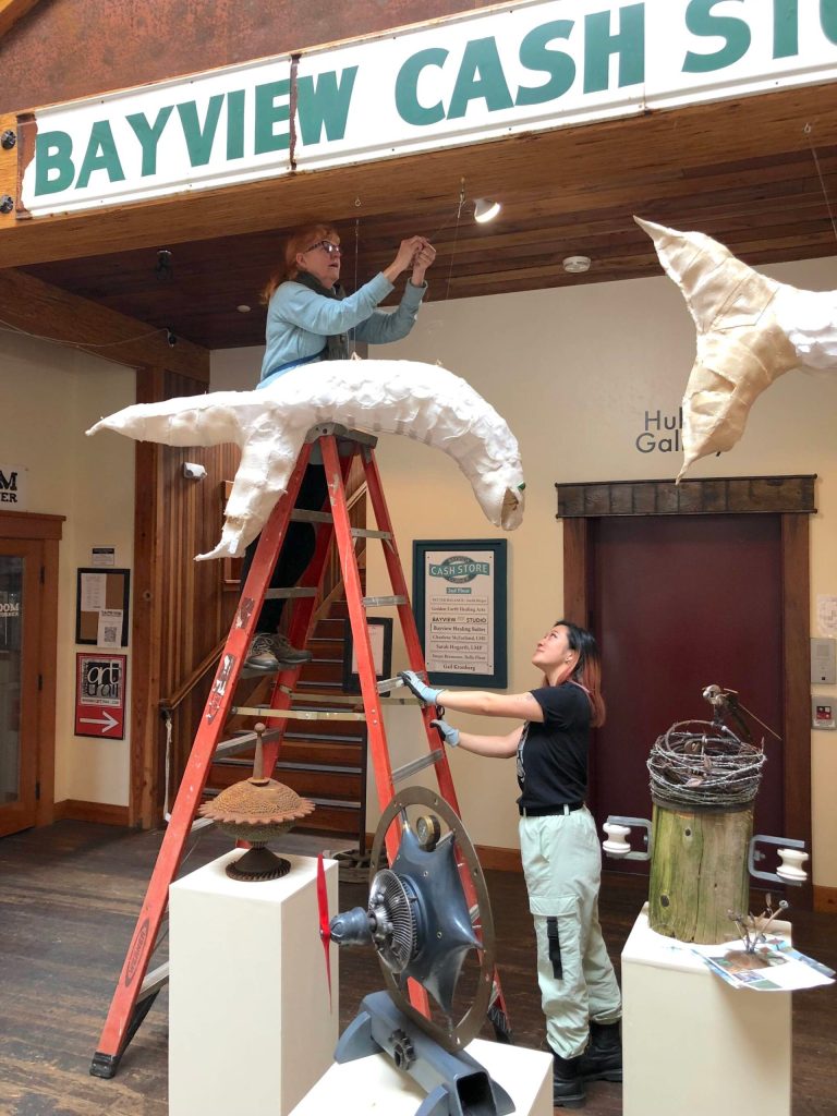 Photo provided
Melissa Koch hangs one of her ghost salmon in the Bayview Cash Store. The installation is made of upcycled fabric, plastic, cane and wax.