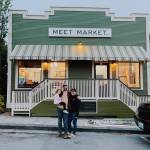 Andrew Ziehl, center, and Cade Roach stand in front of their new business, Meet Market, with their daughter, Eliot. (Photo provided)