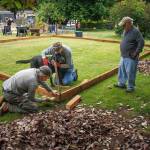 From left to right, Jan-Marc Jouas, Russ DeWolfe and David LaBreque of Rotary Club of South Whidbey Island, with assistance from service dog Theo, work on building an enclosure for a playground in the backyard of the House of Hope.(Photo by David Welton)
