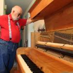 Dennis takes a look at the inside of the piano he built. He had to replace each hammer individually after it fell off a truck in the mid 1970s. (Photo by Karina Andrew / Whidbey News-Times)