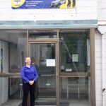 Detective Sgt. Jennifer Gravel stands under the banner advertising Citizen Academy. (Photo by Rachel Rosen/Whidbey News-Times)