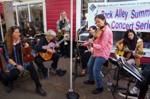 By David Welton
The streets of Langley, as well as the Freeland Library, were filled with music for five days as DjangoFest Northwest arrived. Along with the headlining bands, improvisational sessions sprang to life all over the Village by the Sea. Above, the all-female band Café Impromptu invites audience members to join in making music in front Double Bluff Brewery .