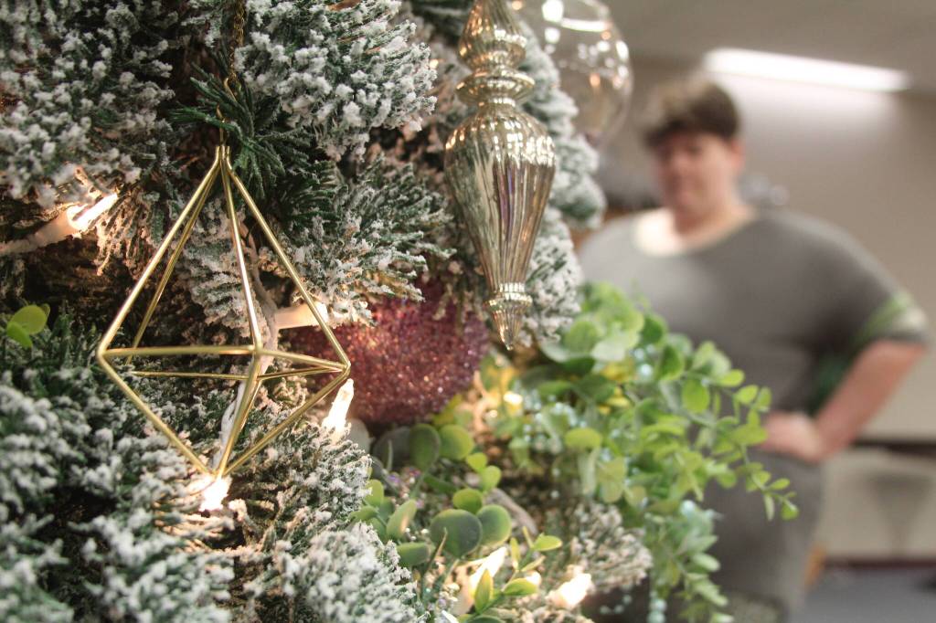 Grayson Akins, a match coordinator for Big Brothers Big Sisters of Island County, decorates a tree for auction at the Festival of Trees.