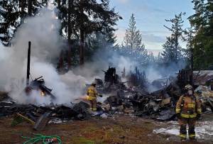 Photo provided
North Whidbey Fire and Rescue firefighters subdue a structure fire on Cerullo Drive the morning of Dec. 3.