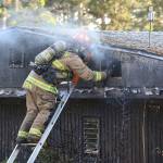 A North Whidbey Fire and Rescue firefighter works to extinguish a residential fire on Deer Park Lane May 25. (Photo by John Fisken)