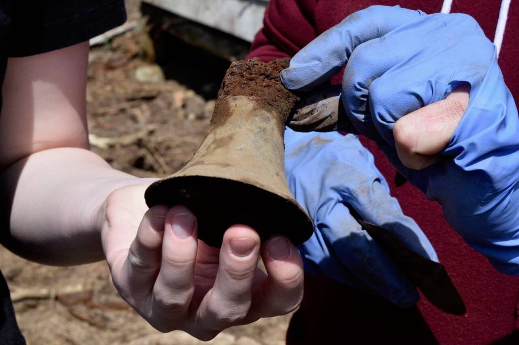 Photo by Patricia Guthrie
Woodhaven School freshman Alicia Jenkins shows off the metal bell she found to property owner Marian Myszkowski.
