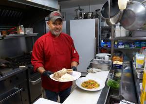 Photo by David Welton
Chef Chris Balora with dishes of kalua pig and Spam fried noodles.