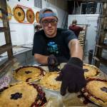 Clint Luetkehans transfers freshly baked pies to a rack that will be wheeled into the cooling room of the Whidbey Pies production facility. (Photo by David Welton)