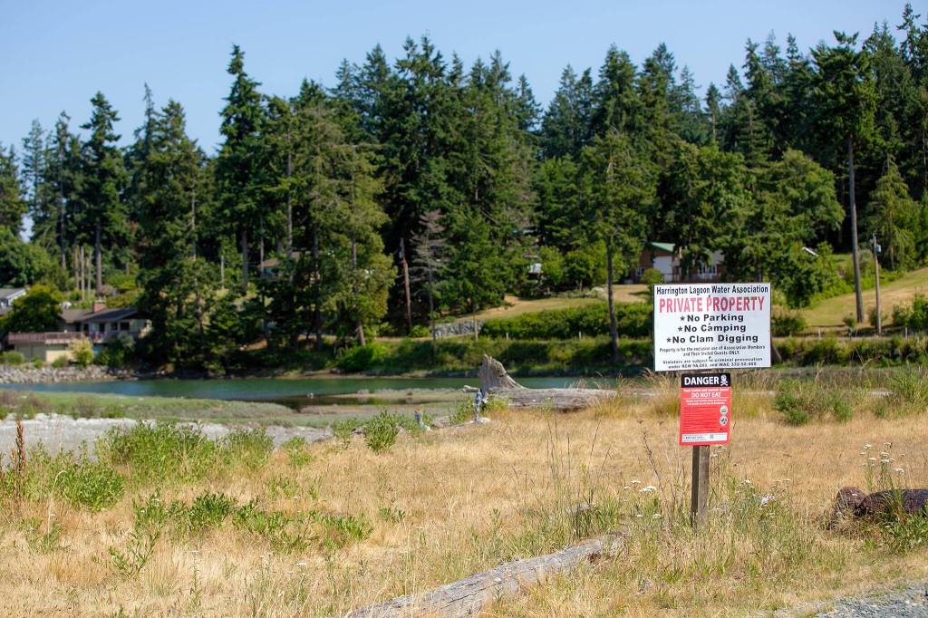 The southern side of the Harrington Lagoon neighborhood is seen beyond a Harrington Lagoon Water Association sign on June 22, 2023, in Coupeville, Washington. (Ryan Berry / The Herald)
