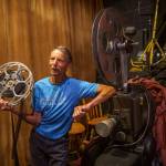 Blake Willeford stands beside the projector that The Clyde Theatre used to show films until moving to a digital format in 2011.
