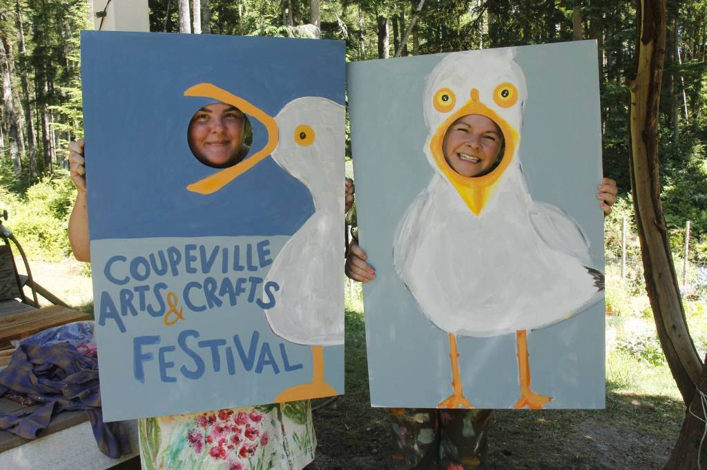 Meredith Cannon, left, and Rachel Phillips show off the cornhole boards that they painted for the upcoming Coupeville Arts and Crafts Festival. (Photo by Kira Erickson/South Whidbey Record)