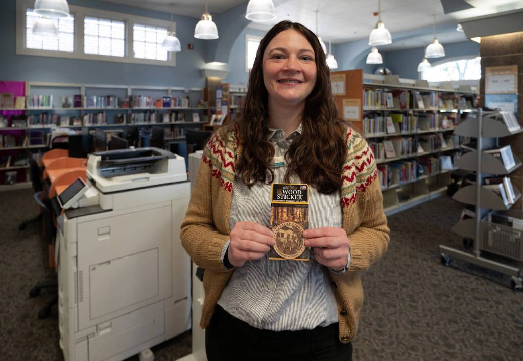 Langley Library Manager Kaley Costello with stickers commemorating the librarys 100th birthday. (Photo by David Welton)