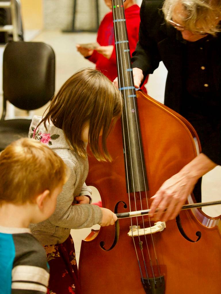 Kids try playing a double bass during a past instrument petting zoo. (Photo provided)