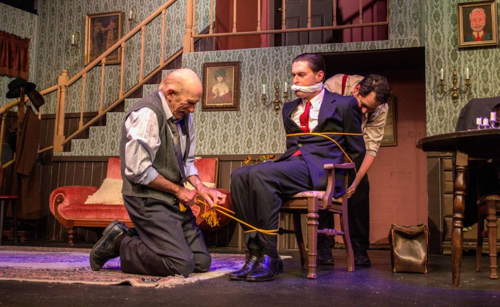 At left, Dr. Einstein (played by Kevin Wm Meyer) helps his evil client Jonathan Brewster (played by Nate Edmiston) tie up Mortimer Brewster (played by Riley Stowell). (Photo by Luisa Loi)