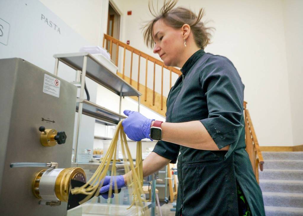 Echo makes bucatini as her hair is blown by a fan in the machine that keeps the noodles from sticking together as they come out. (Photo by David Welton)
