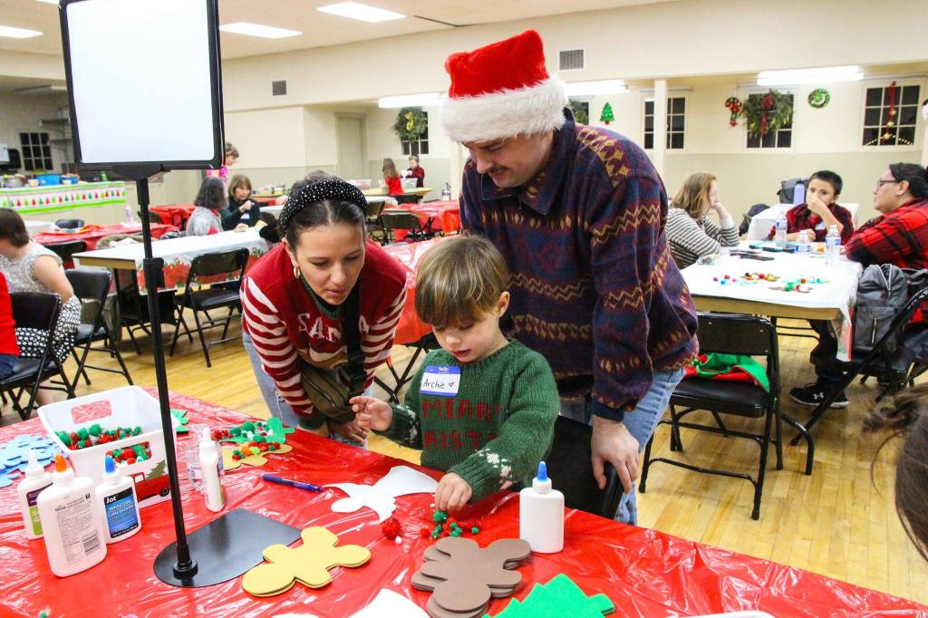 Archie Ascione shows his parents how to decorate a Christmas angel. (Photo by Luisa Loi)