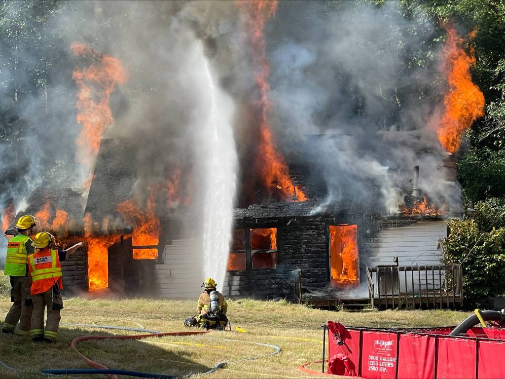 Firefighters from South Whidbey Fire/EMS practice extinguishing a blaze during a training session. The fire district is planning to ask voters to approve a levy lid lift in 2024 to fund the hiring of more personnel and the replacement of aging equipment. (Photo by Karley Diffie)