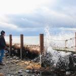 Marie Francos husband, Lenny, avoids the splash while taking a short break from cutting a log brought by Tuesdays storm. (Photo by Luisa Loi)