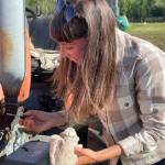 Organic Farm School student Abby Wood checks the oil on a tractor. Students learn a number of skills during the intensive program, including how to repair farm equipment. (Photo provided)