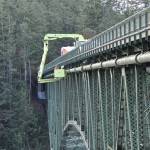 On January 11, 2024, the City of Oak Harbor Public Works Department in partnership with the Washington State Department of Transportation completes repairs on the City’s 1971 water transmission main that hangs from the Deception Pass Bridge.  The water main provides drinking water to the City as well as to the Navy base.  The repair was to the air vacuum valve which allows large volumes of air to be exhausted from or admitted into a water pipeline preventing loss of pressure or possible pipeline damage. (Photo courtesy of City of Oak Harbor Public Works)
