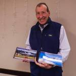 Photographer Joe Manhardt holds at his books, Naval Air Station Whidbey Island and Naval Outlying Landing Field Coupeville. (Photo by Sam Fletcher)