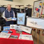 Photographer Joe Manhardt poses at his booth at the book launch of "Naval Air Station Whidbey Island" at Pacific Northwest Naval Air Museum on Saturday. (Photo courtesy of Pacific Northwest Naval Air Museum)
