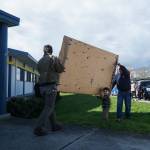 Artist Nick Mann (left), his son George Mann (middle) and faculties worker Tom Wade (right) bring a panel of Song of the Salish Sea into City Hall. (Photo by Sam Fletcher)