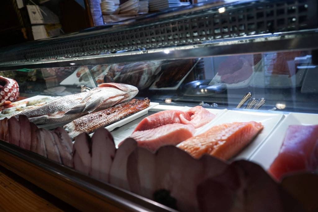 From behind the glass poses the meaty arms of an octopus, sea bream from Japan, blue-fin tuna from the Mediterranean, King salmon from New Zealand and Johnston himself preparing it all. (Photo by Sam Fletcher)