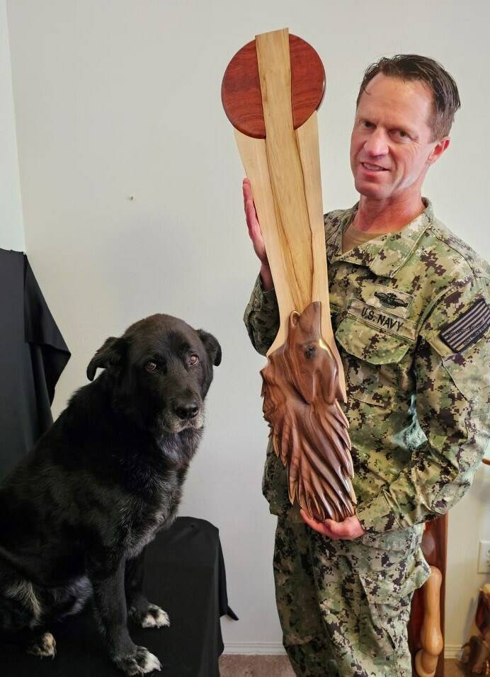 Chad Pilkington and his dog, Bane, pose with a wolf sculpture. Pilkington, 51, worked for 20 years as a corpsman biomed repair technician for the navy, repairing hospital equipment. He moved to Whidbey in 2018, and retired from the Navy in August 2023. (Photo provided)