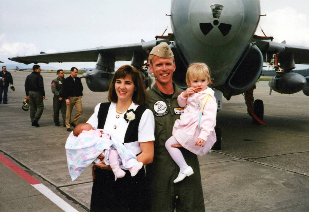 Sherri Pierson, left, holds her daughter Alyssa, and Randy Pierson holds his daughter Brooke during the VAQ-137 Rooks Homecoming.