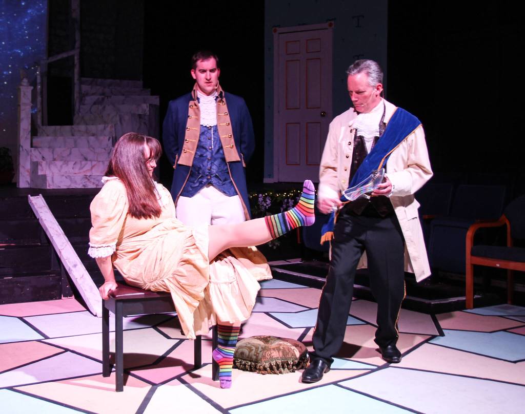 A peasant woman impatiently waits for Lionel (Bill Larsen) to help her into the glass shoe in front of a perplexed Prince Christopher (Jordan Kingma). But could this be the fair maiden the young man is desperately looking for? (Photo by Luisa Loi)