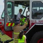 Photo by Caitlyn Anderson
Navy firefighter Dakota Montoya lifts Oliver Brower out of an E-ONE ARFF at the Touch-a-Truck event.