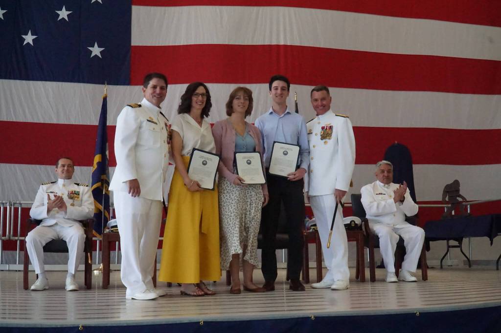 Commanding Officer Capt. Eric Hanks (left) and Rear Admiral Mark Sucato (right) pose with the Hanks family at Thursdays change of command ceremony. (Photo by Sam Fletcher)