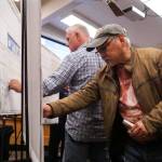 John Kung, a new Oak Harbor resident, puts a sticker in favor of a port district to support the marina. (Photo by Sam Fletcher)