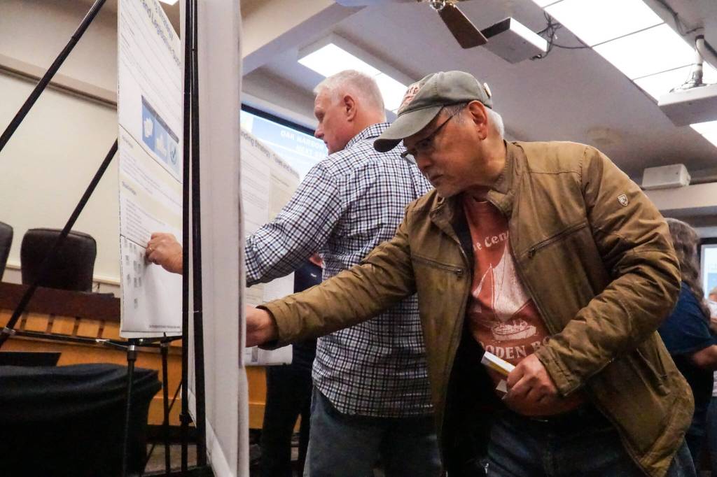 John Kung, a new Oak Harbor resident, puts a sticker in favor of a port district to support the marina. (Photo by Sam Fletcher)