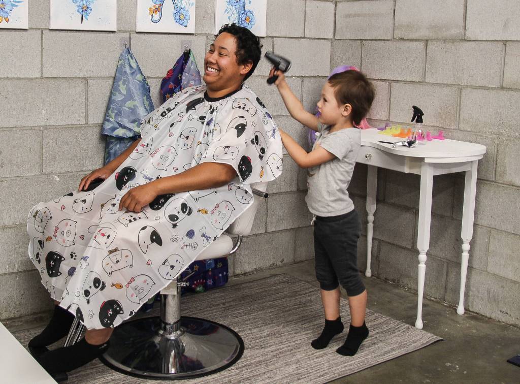 (Photo by Luisa Loi)
Jane Carter gives her mom, Maddie Evans, a haircut at Imagination Cove, a family center owned by two military spouses, Jaylynn Sybrant and Mala Sooknanan. The museum opened in July.
