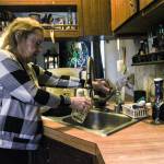 Denis Muller, a resident of Parkwood Manor Mobile Home Park, pours a glass of water that reports show have unsatisfactory level of coliform. (Photo by Sam Fletcher)