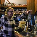 Denis Muller, a resident of Parkwood Manor Mobile Home Park, holds a glass of water that reports show have unsatisfactory level of coliform. (Photo by Sam Fletcher)