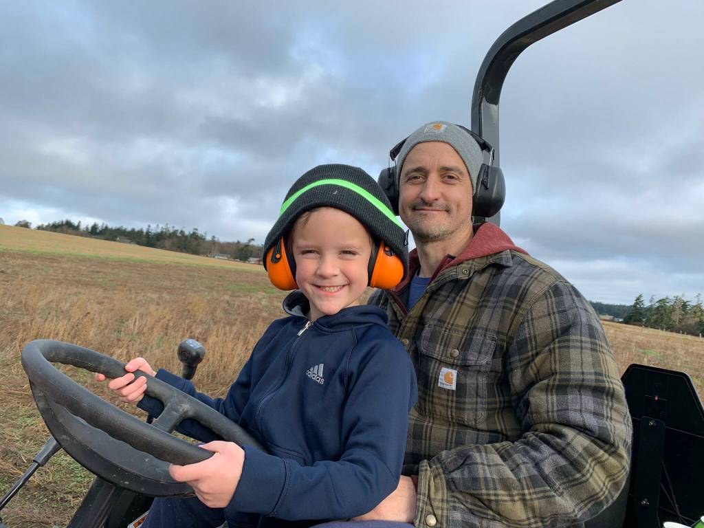 Photo provided
Bart Crowder, president of the Farm Bureau, drives a tractor with his son on the 1902 Ranch in Coupeville.