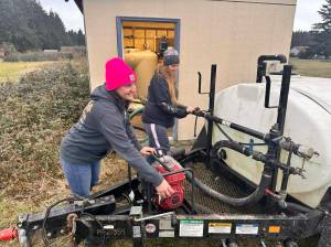 Photo provided
Julee May, left, and Christina Linares use water from the portable tank and add it to the reservoir in the well house.